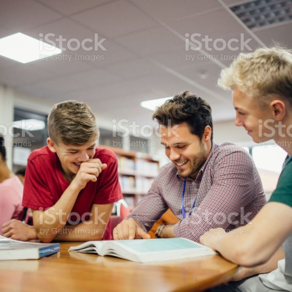 Students are engaging with their teacher during a lesson. He is helping them with some of their written work.